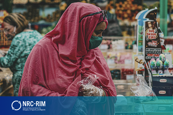 East African woman in a pink hijab and green face mask grocery shopping