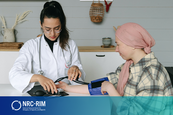 A young woman doctor takes the blood pressure of a refugee woman in a pink head scarf and flannel collared shirt