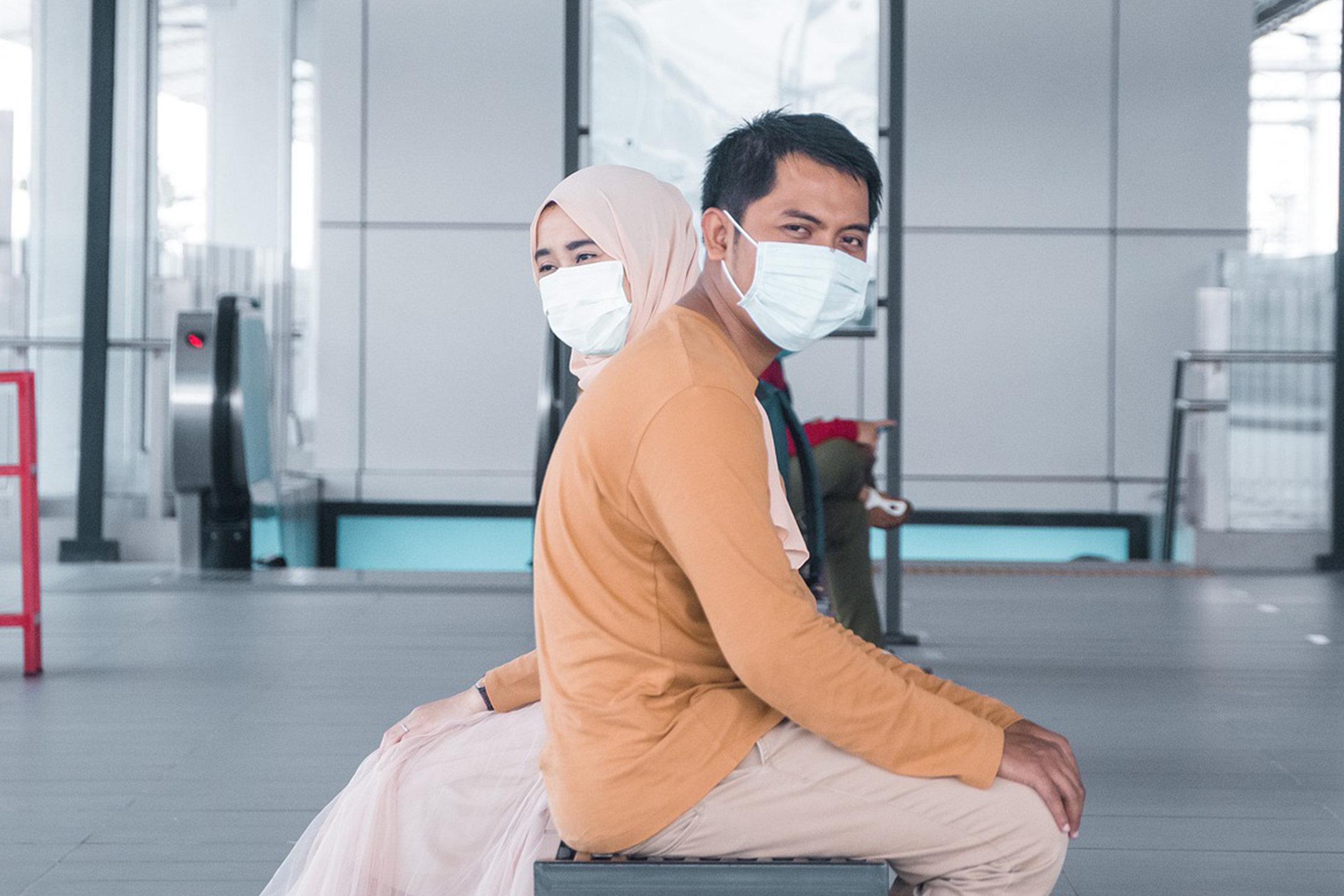 Two people sitting together but facing opposite and wearing face masks