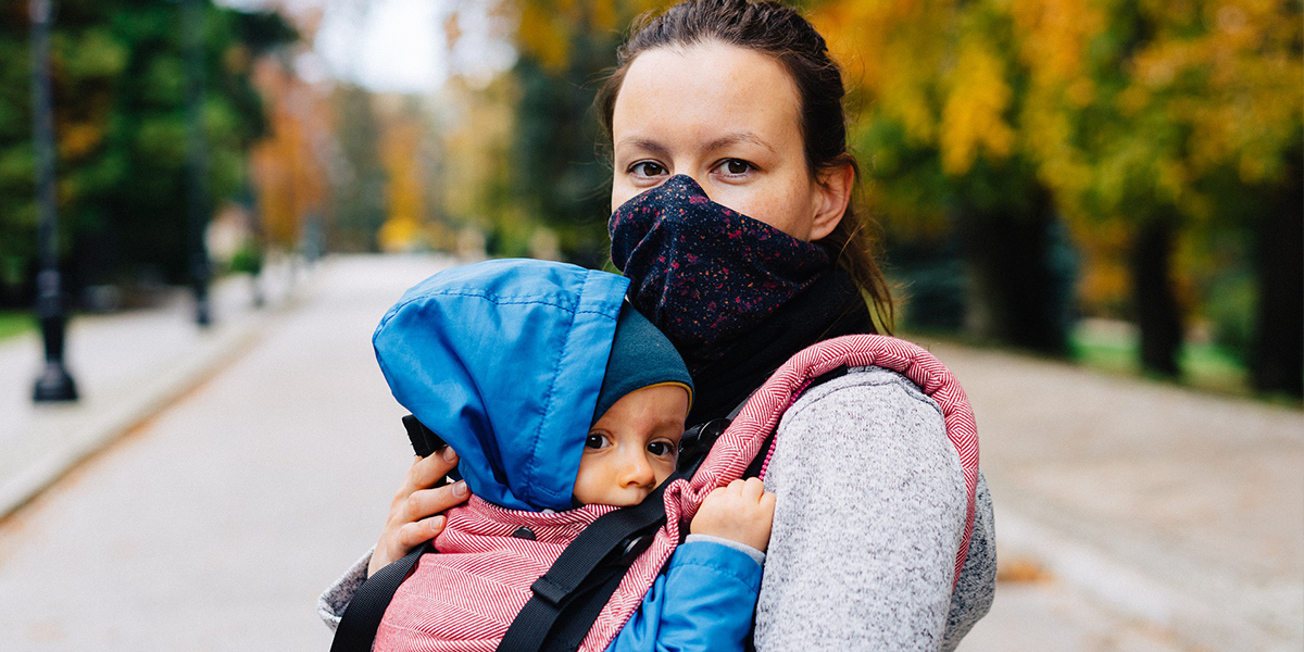 Young woman with face covering holding baby