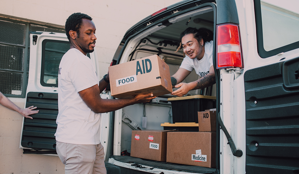 Two men unloading food, medicine and other items from a van during volunteer event