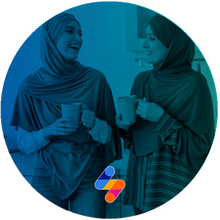 Two women in hijabs chat over coffee